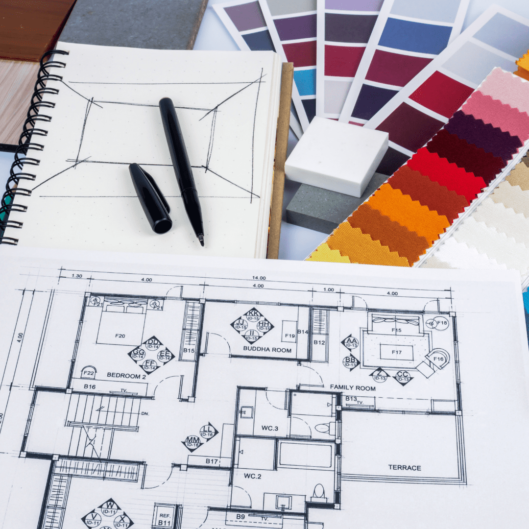 Interior design workspace with architectural floor plan, color swatches, sketch notebook, and black markers for home design planning