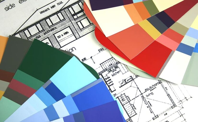 Architectural blueprints with color paint swatches fanned across the plans for home design selection