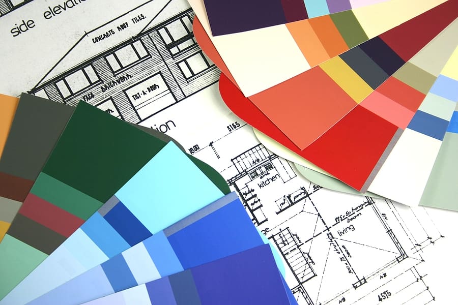 Architectural blueprints with color paint swatches fanned across the plans for home design selection
