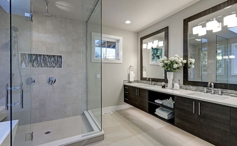 Spacious modern bathroom with gray tile walk-in shower, dark wood double vanity with white countertop, large mirrors, white flowers, and skylights