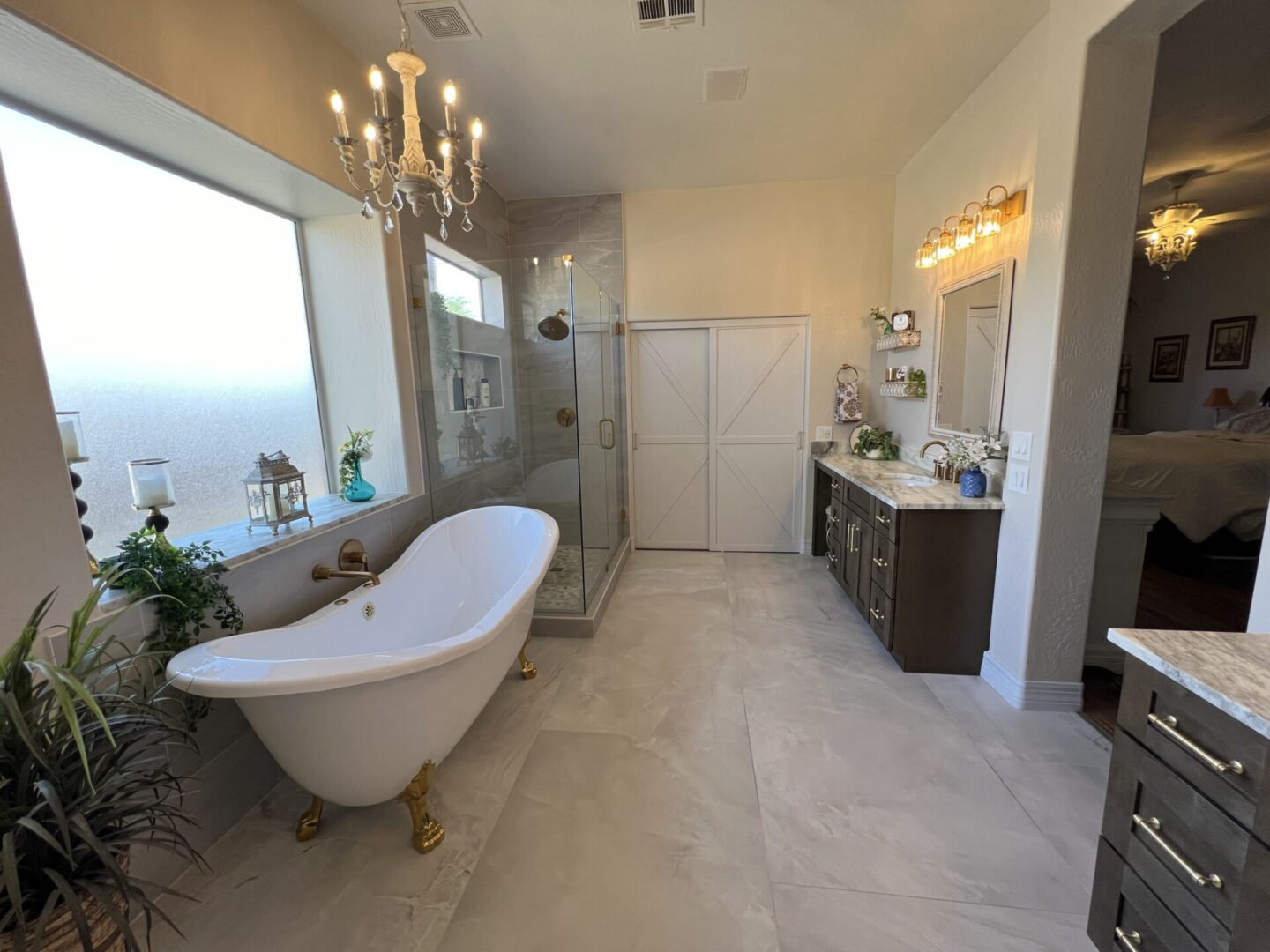 Luxurious master bathroom with freestanding soaking tub, walk-in shower, dual vanity, chandelier, and marble flooring