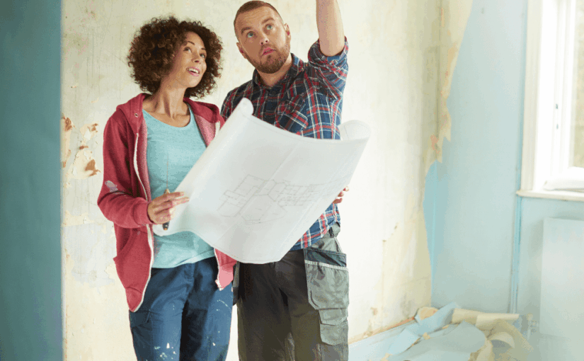 Couple reviewing blueprint in unfinished room during home renovation project