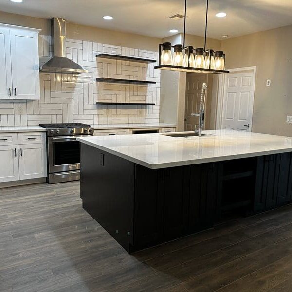 Modern kitchen with black island, white countertops, white cabinetry, subway tile backsplash, stainless steel appliances, and pendant lighting