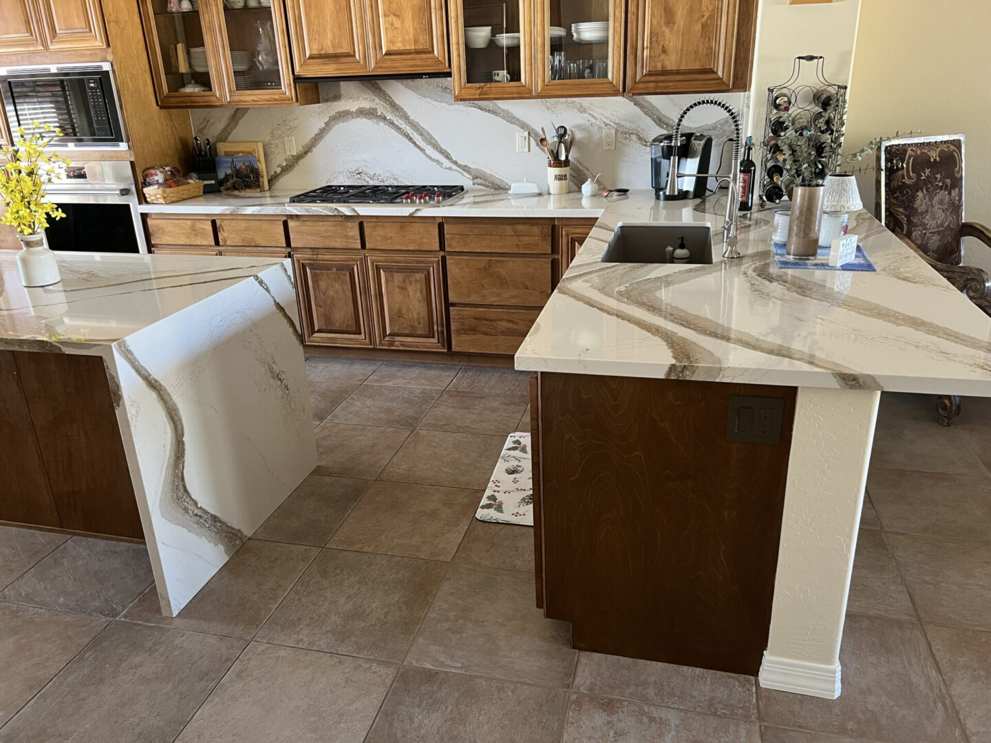 Spacious kitchen with marble countertops, wood cabinetry, and two islands with white and dark wood bases in Cincinnati home