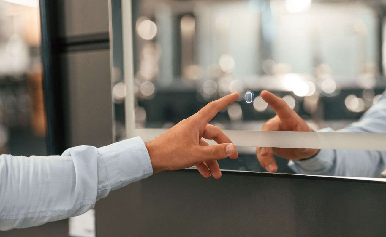 Person in white shirt pointing at interactive touchscreen display with blurred urban background