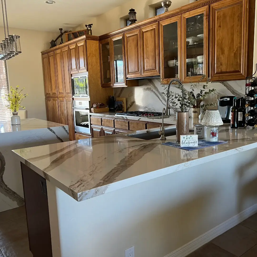 Luxurious modern kitchen with marble-topped island, wood cabinetry, stainless steel appliances, and decorative countertop accessories in neutral tones
