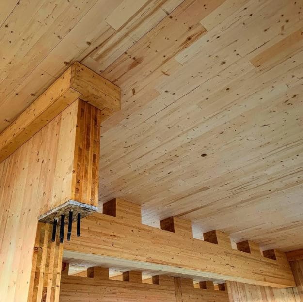 Interior wooden beam construction with spruce ceiling and support posts in modern log cabin or timber frame building